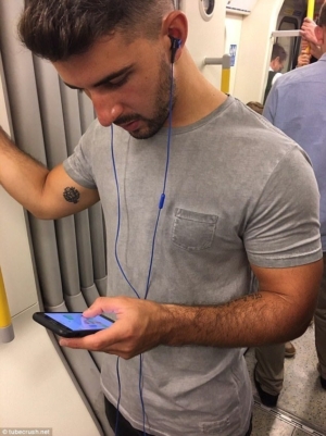 Eye Candy: photo of well-built young man with smartphone on London Underground.